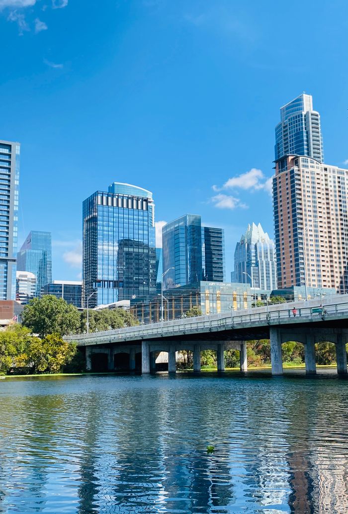 Beautiful view of Austin skyline reflected in the river under a clear blue sky.